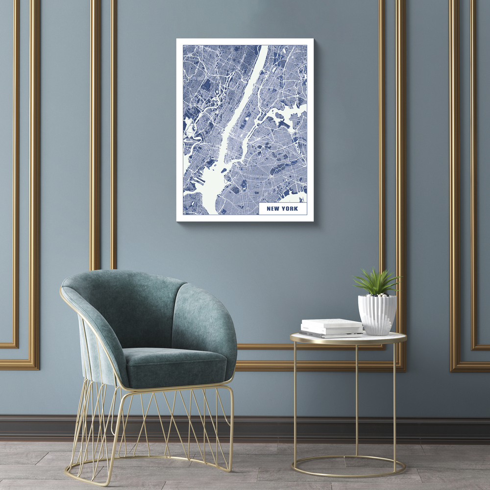 Affiche du plan de New York bleu et blanc sur un mur gris-bleu à moulures dorées, au-dessus d’un fauteuil