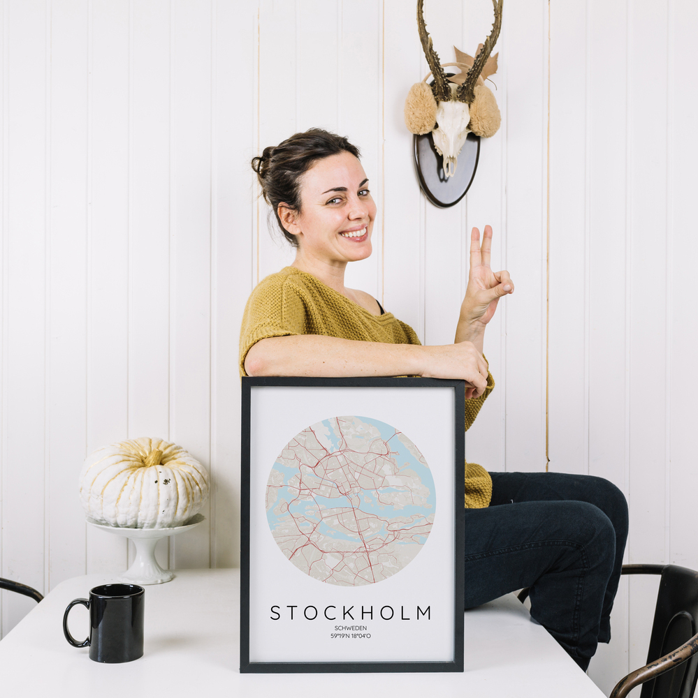 Affiche avec plan circulaire de Stockholm dans un cadre noir, sur une table blanche à côté d’une tasse