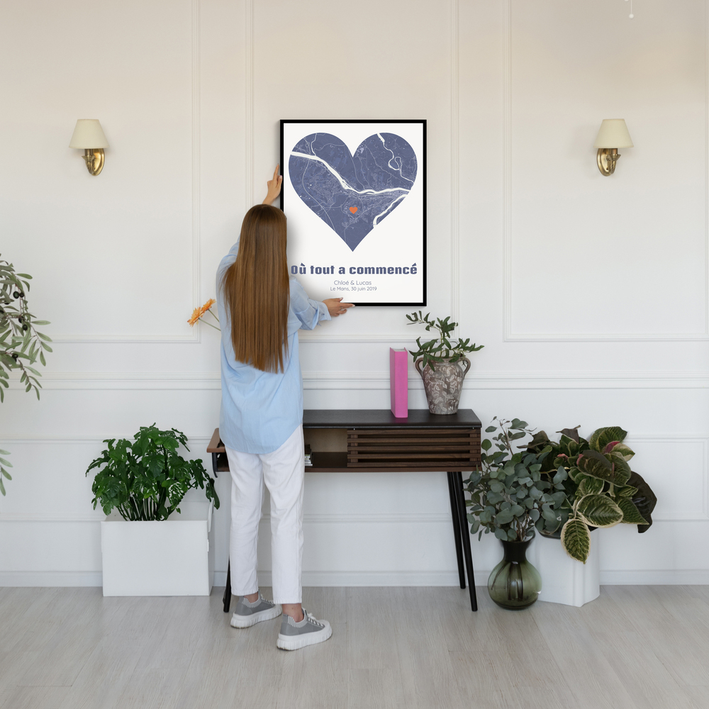 Plan de ville bleu en forme de cœur dans un cadre noir, au mur au-dessus d’une console entourée de plantes