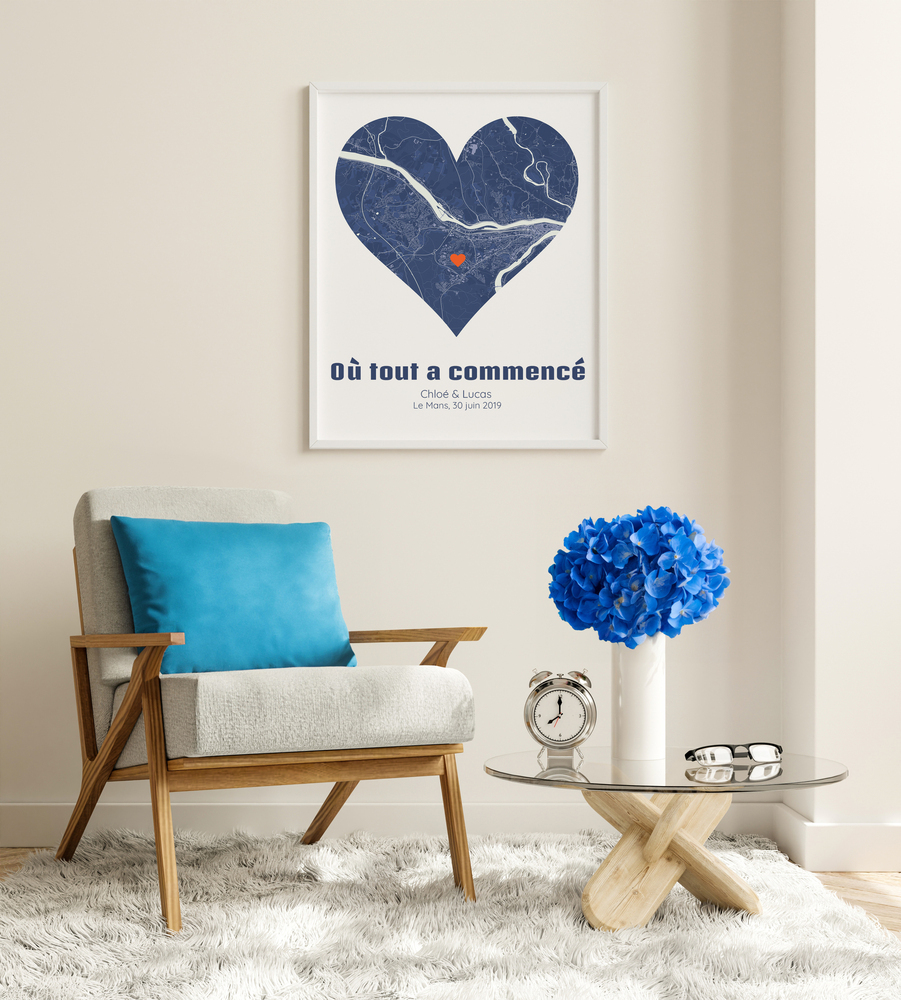 Affiche de ville en forme de cœur encadrée en blanc au-dessus d’un fauteuil, une idée cadeau pour un couple