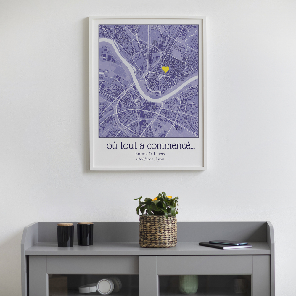 Carte de ville violette personnalisée avec cœur jaune, dans un cadre blanc au-dessus d’un buffet gris.