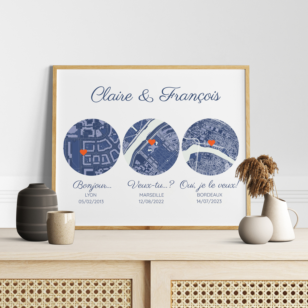 Affiche aux trois plans de ville bleus et repères en cœur, encadrée en bois clair sur un buffet en cannage